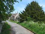 Cotswold stone cottages beside a lane that is awash with cow parsley bloom